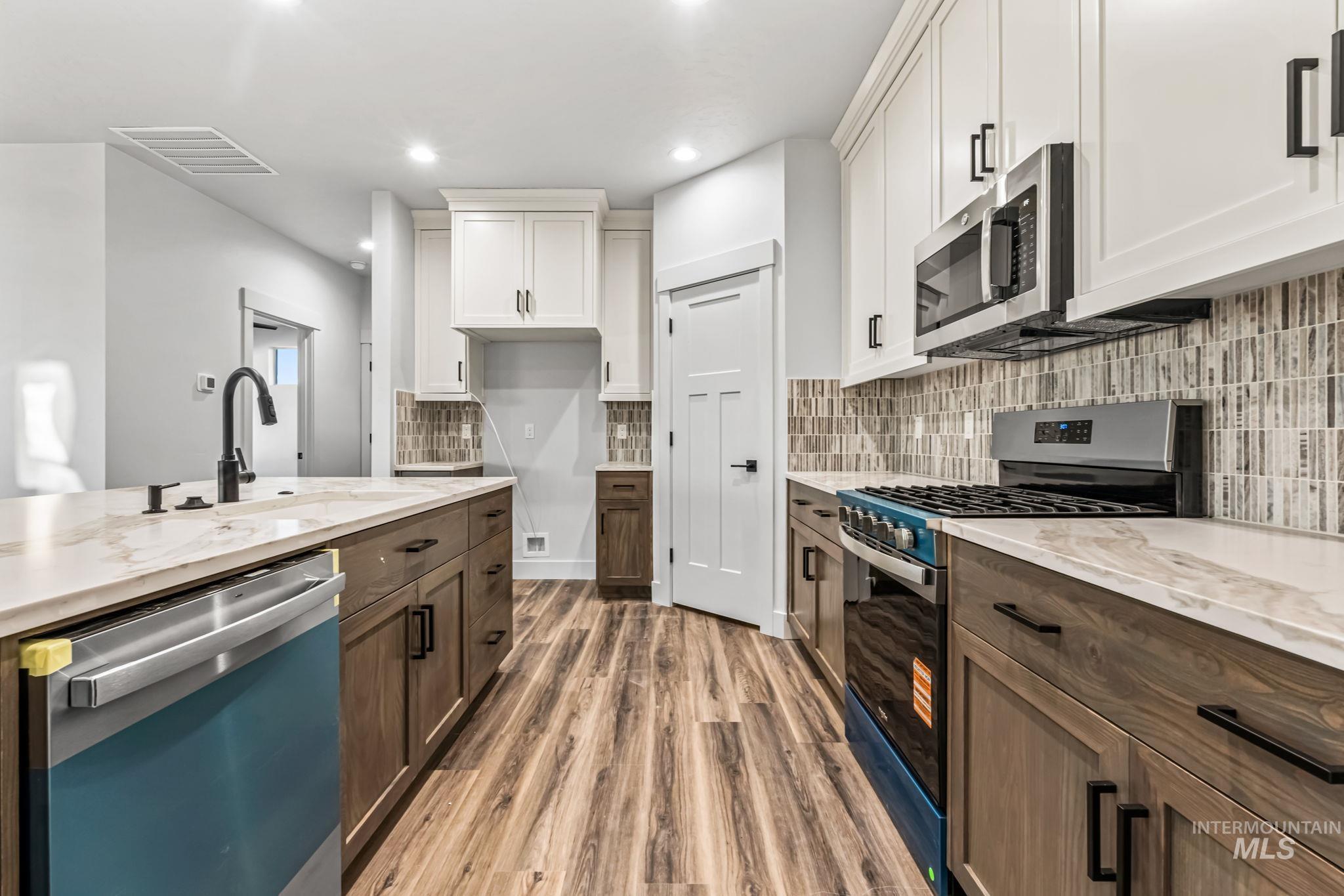 2905 Cypress Point Payette, ID 83661 - Photo 5 of 26 Kitchen featuring stainless steel appliances, white cabinetry, light wood finished floors, light stone countertops, and recessed lighting