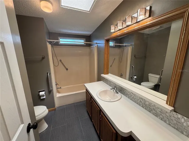 a bathroom with a sink a toilet a mirror and shower