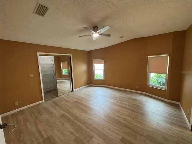 a view of empty room with wooden floor and fan