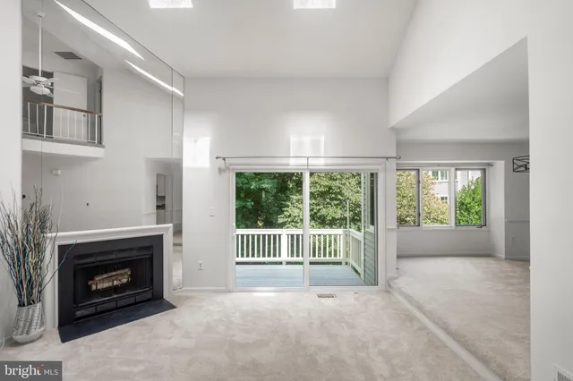 a view of an empty room with wooden floor fireplace and a window