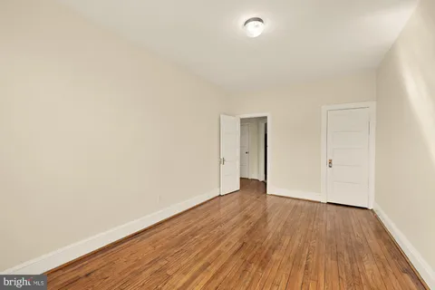 a view of an empty room with wooden floor and closet