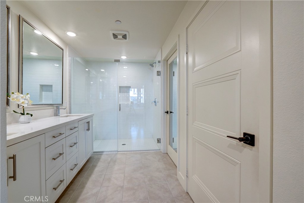 16235 Dawn Way, Unit 203 Tustin, CA 92782 - Photo 44 of 74 a bathroom with a double vanity sink a mirror and a shower