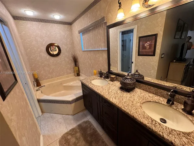 a bathroom with a granite countertop double vanity sink and a bathtub