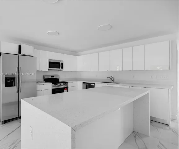 a kitchen with stainless steel appliances a refrigerator sink and microwave