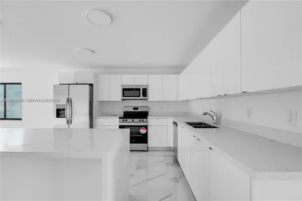 a kitchen with stainless steel appliances a refrigerator sink stove and white cabinets