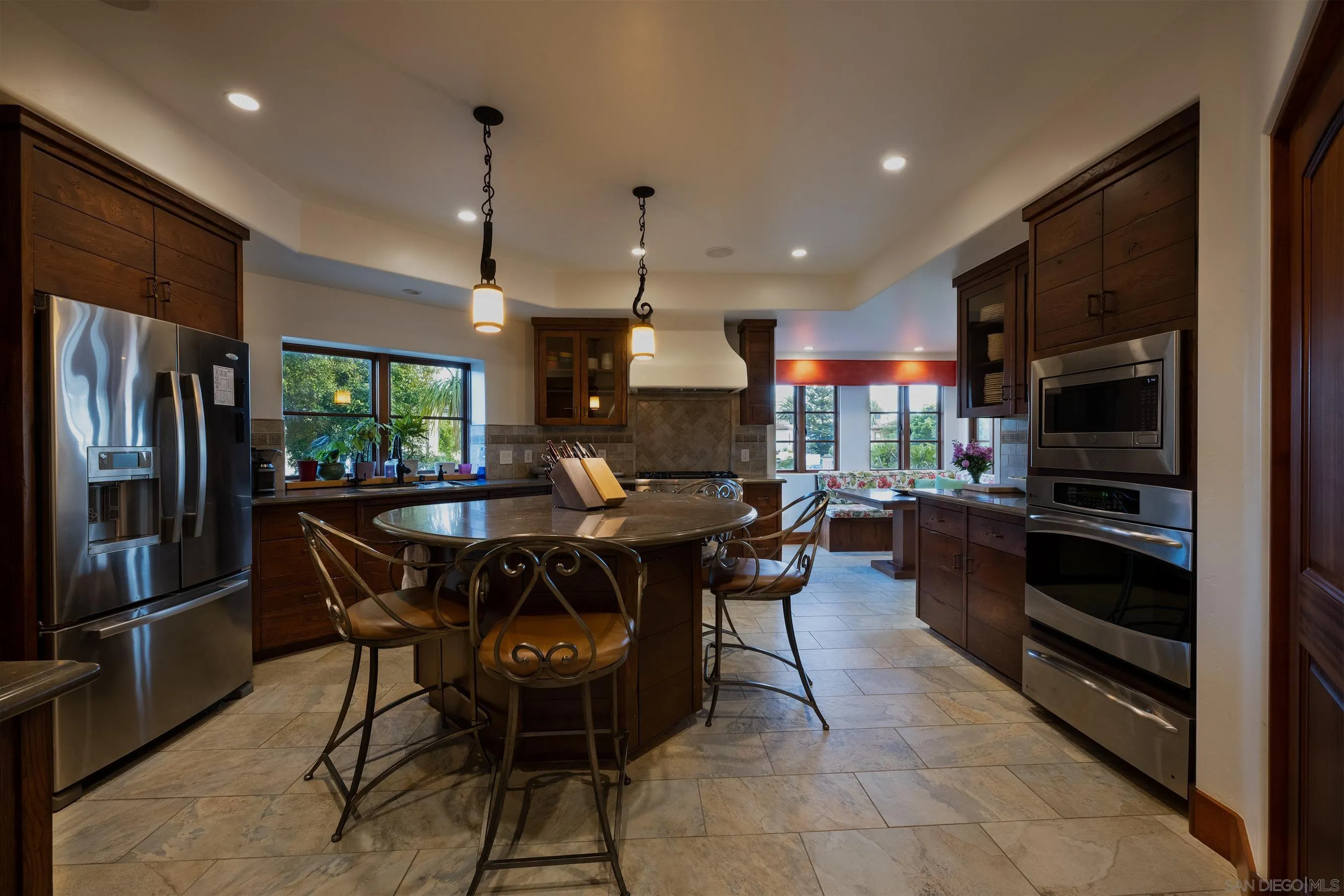 1245 Park Row La Jolla, CA 92037 - Photo 12 of 23 a kitchen with stainless steel appliances kitchen island granite countertop a refrigerator a stove a sink a dining table and chairs with wooden floor