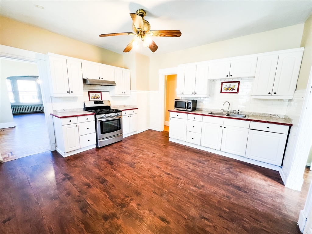 68 Forest Park Avenue Springfield, MA 01108 - Photo 15 of 19 a kitchen with granite countertop a stove a sink and white cabinets with wooden floor