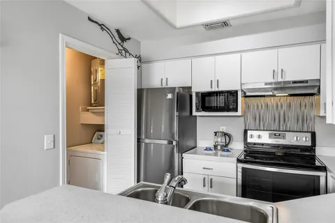 a kitchen with white cabinets sink and stainless steel appliances