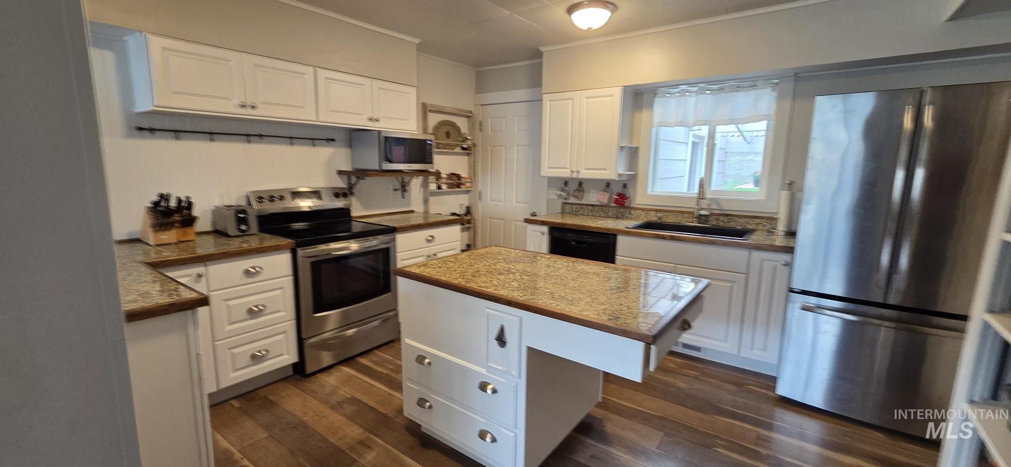1269 Main Street Pomeroy, WA 99347 - Photo 16 of 38 Kitchen with stainless steel appliances, white cabinets, crown molding, a kitchen island, and dark wood-style floors