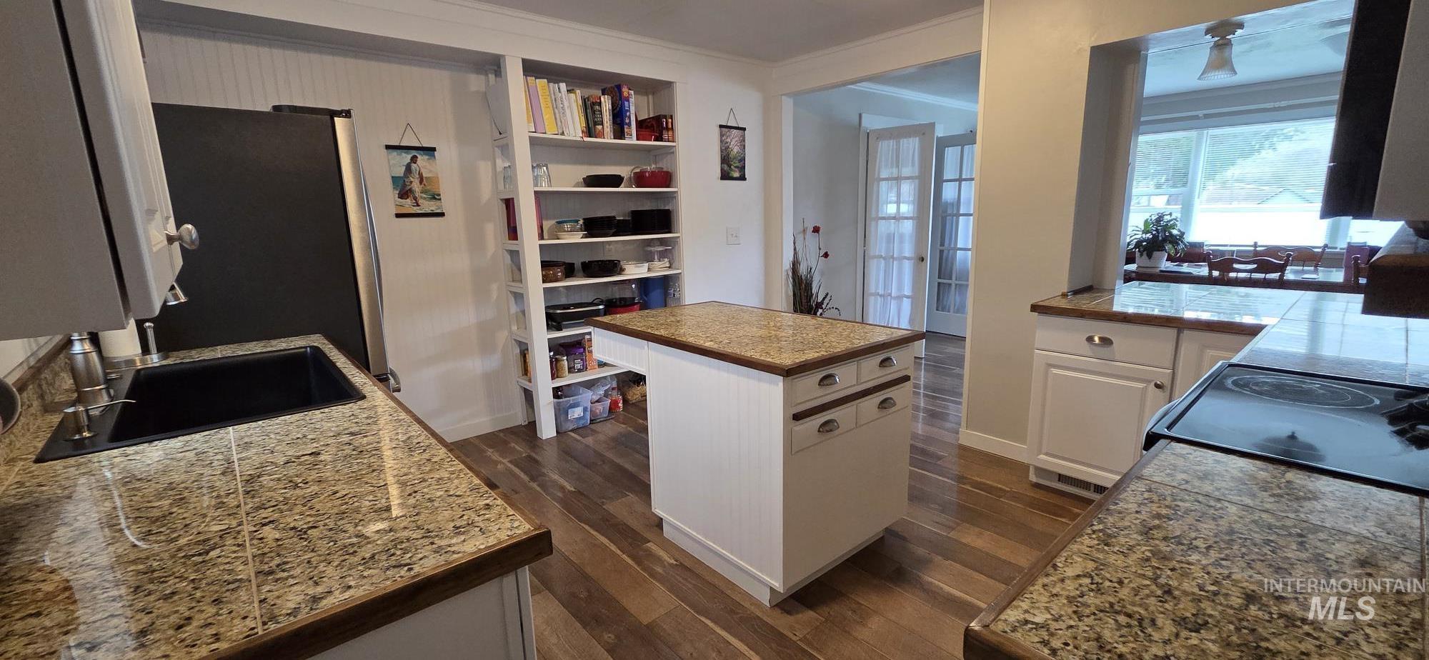 1269 Main Street Pomeroy, WA 99347 - Photo 17 of 38 Kitchen featuring tile countertops, dark wood-type flooring, ornamental molding, white cabinetry, and freestanding refrigerator