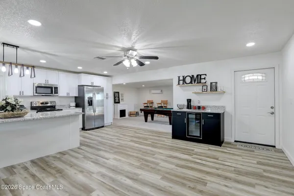 a kitchen with stainless steel appliances kitchen island granite countertop a refrigerator a stove top oven a dining table and chairs with wooden floor