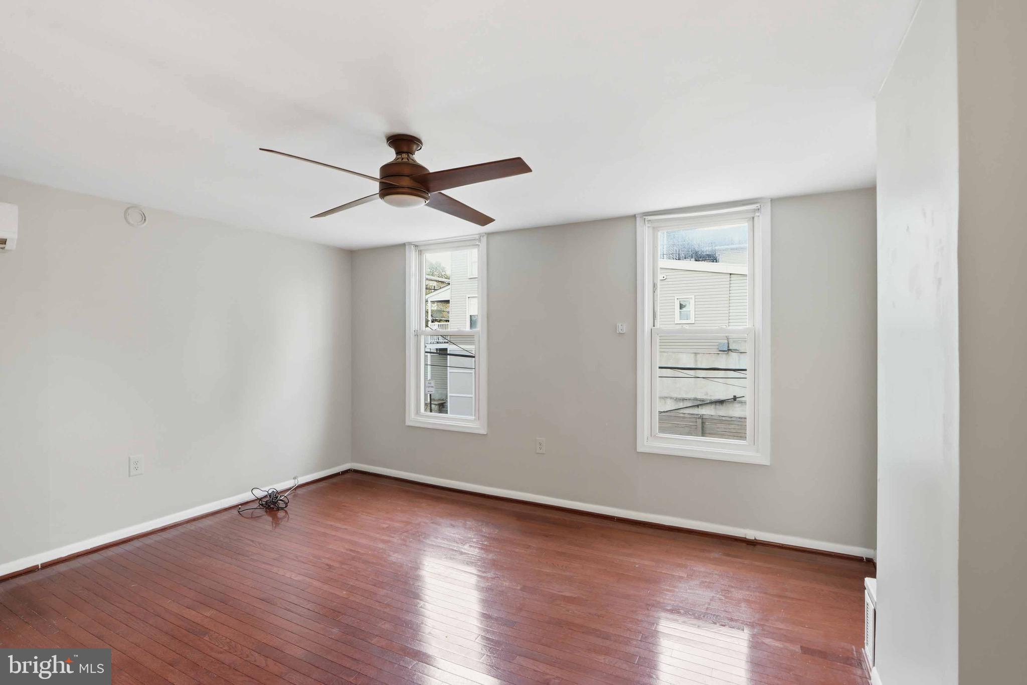3544 Ash Street Baltimore, MD 21211 - Photo 14 of 17 an empty room with wooden floor chandelier fan and windows
