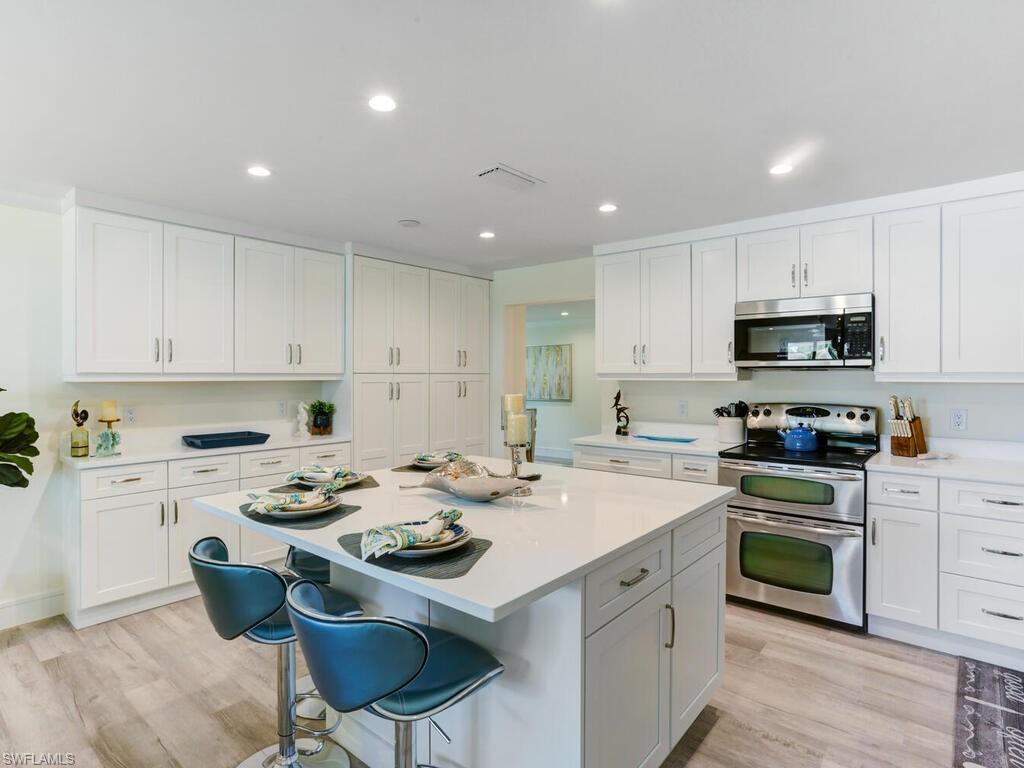 1279 10th Avenue North Naples, FL 34102 - Photo 11 of 31 a kitchen with a stove a sink a dining table and chairs
