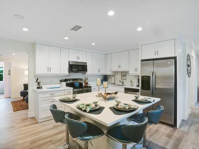 a kitchen with a dining table cabinets appliances and wooden floor