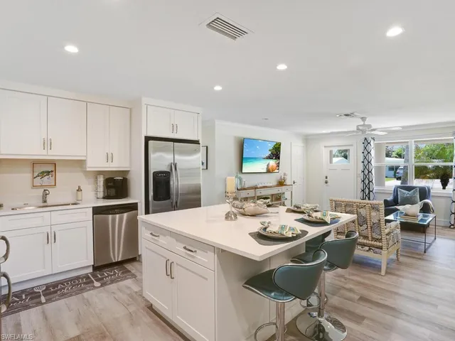 a kitchen with a sink stove and white cabinets with wooden floor
