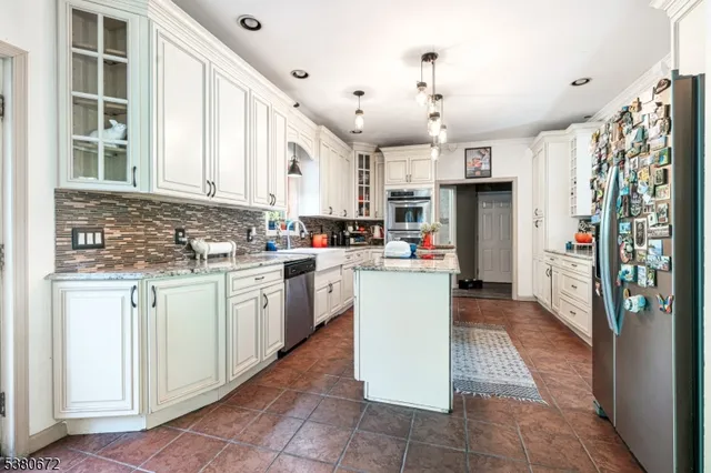 a kitchen with kitchen island granite countertop a sink appliances cabinets and a counter top space