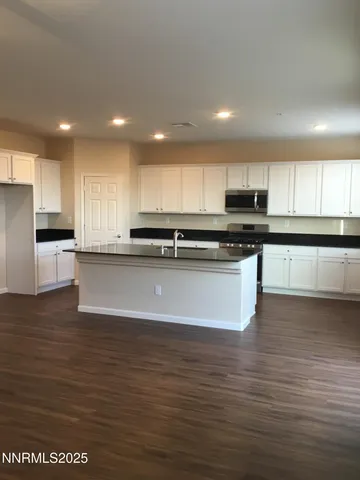 a large kitchen with stainless steel appliances granite countertop a stove a sink and a microwave