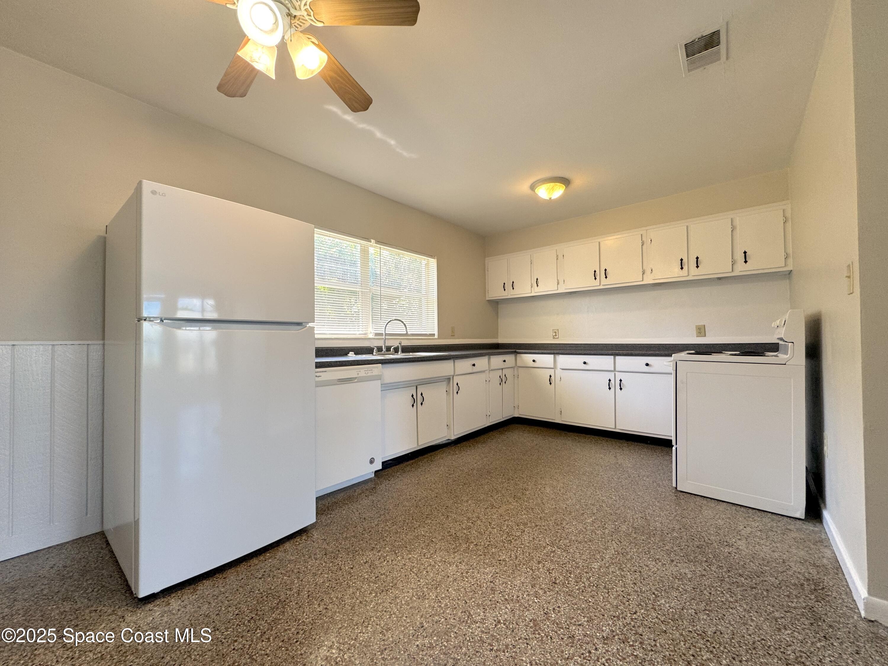 317 3rd Avenue Indialantic, FL 32903 - Photo 6 of 18 a kitchen with white cabinets and white appliances