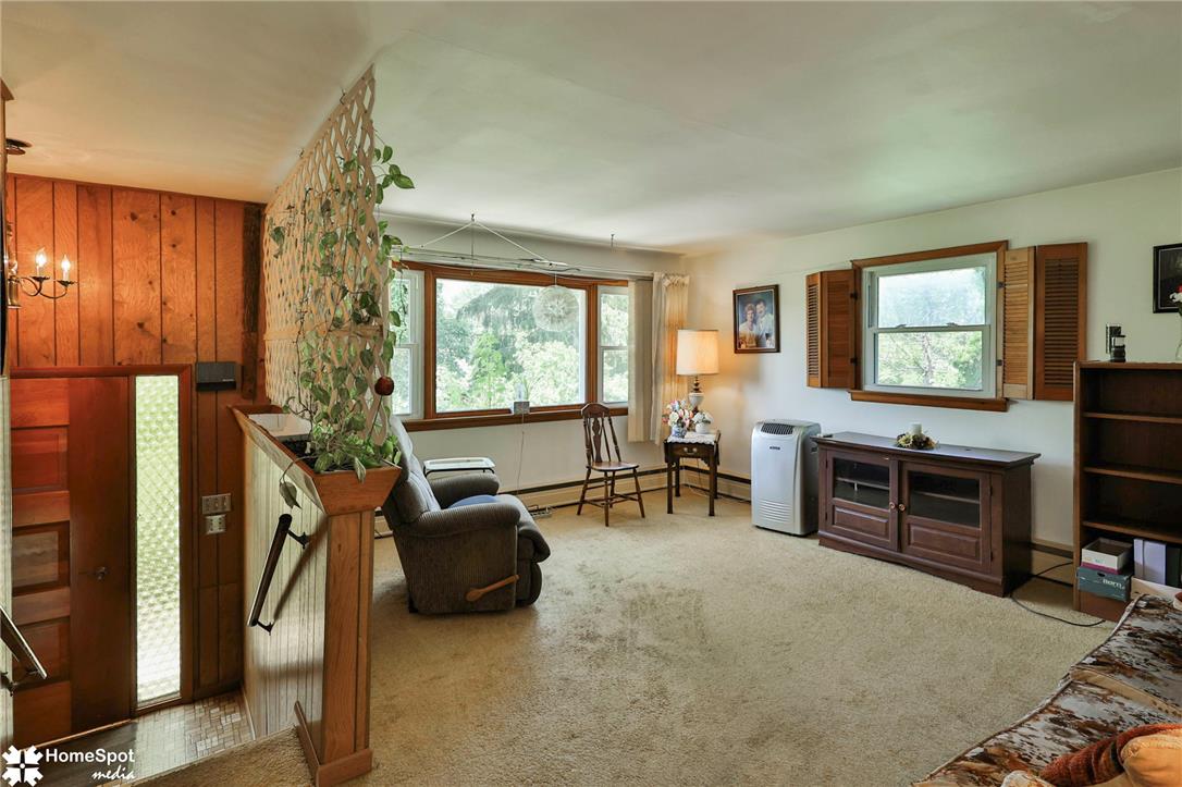 6054 Old Hickory Road Coopersburg, PA 18036 - Photo 10 of 48 A spacious carpeted living area features wood paneling and views of the surrounding greenery.