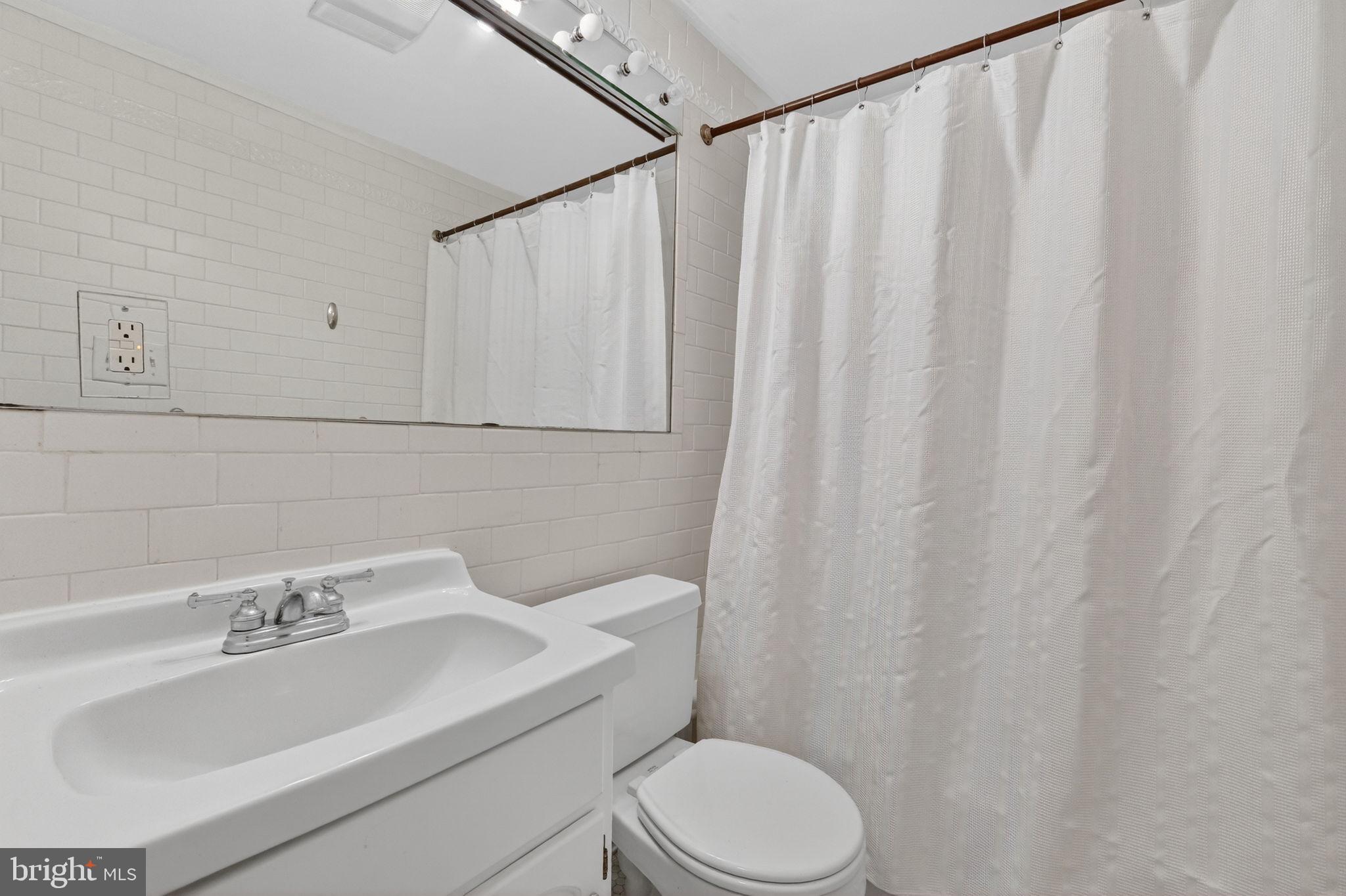 1944 Calvert Street Northwest Washington, DC 20009 - Photo 75 of 85 a bathroom with a sink a toilet and shower curtain