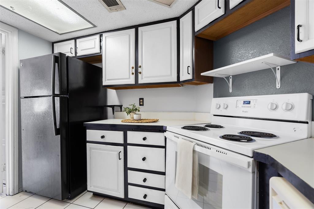 5590 Spring Valley Road, Unit H 203 Dallas, TX 75254 - Photo 8 of 27 Kitchen featuring white cabinetry with black trim, a white electric range, and a black refrigerator