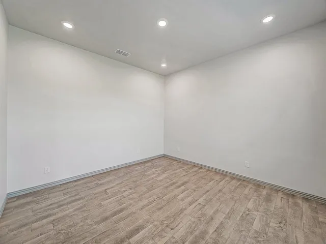 an empty room with wooden floor and fan