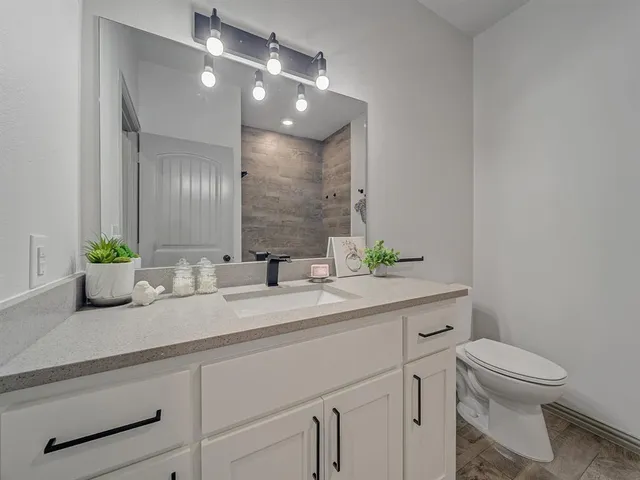 a bathroom with a granite countertop toilet sink and mirror