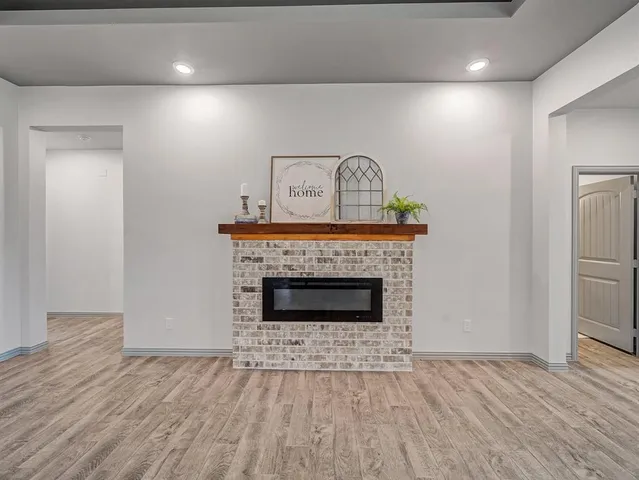 a view of an empty room with wooden floor and a fireplace