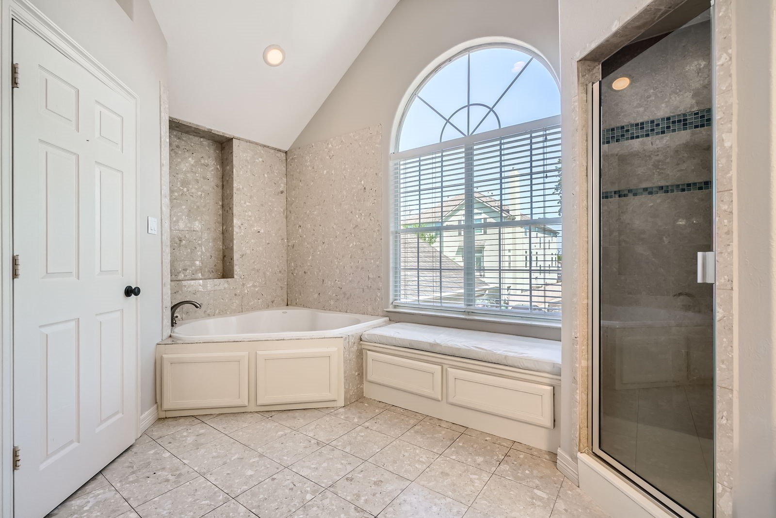 806 East 29th Street Houston, TX 77009 - Photo 16 of 30 This primary bathroom features a spacious soaking tub, a large arched window for natural light, a separate glass-enclosed shower, and elegant tile flooring.