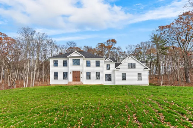 a view of a white house with a big yard and large trees