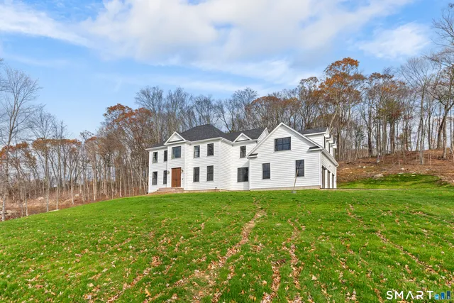 a front view of a house with a garden and trees