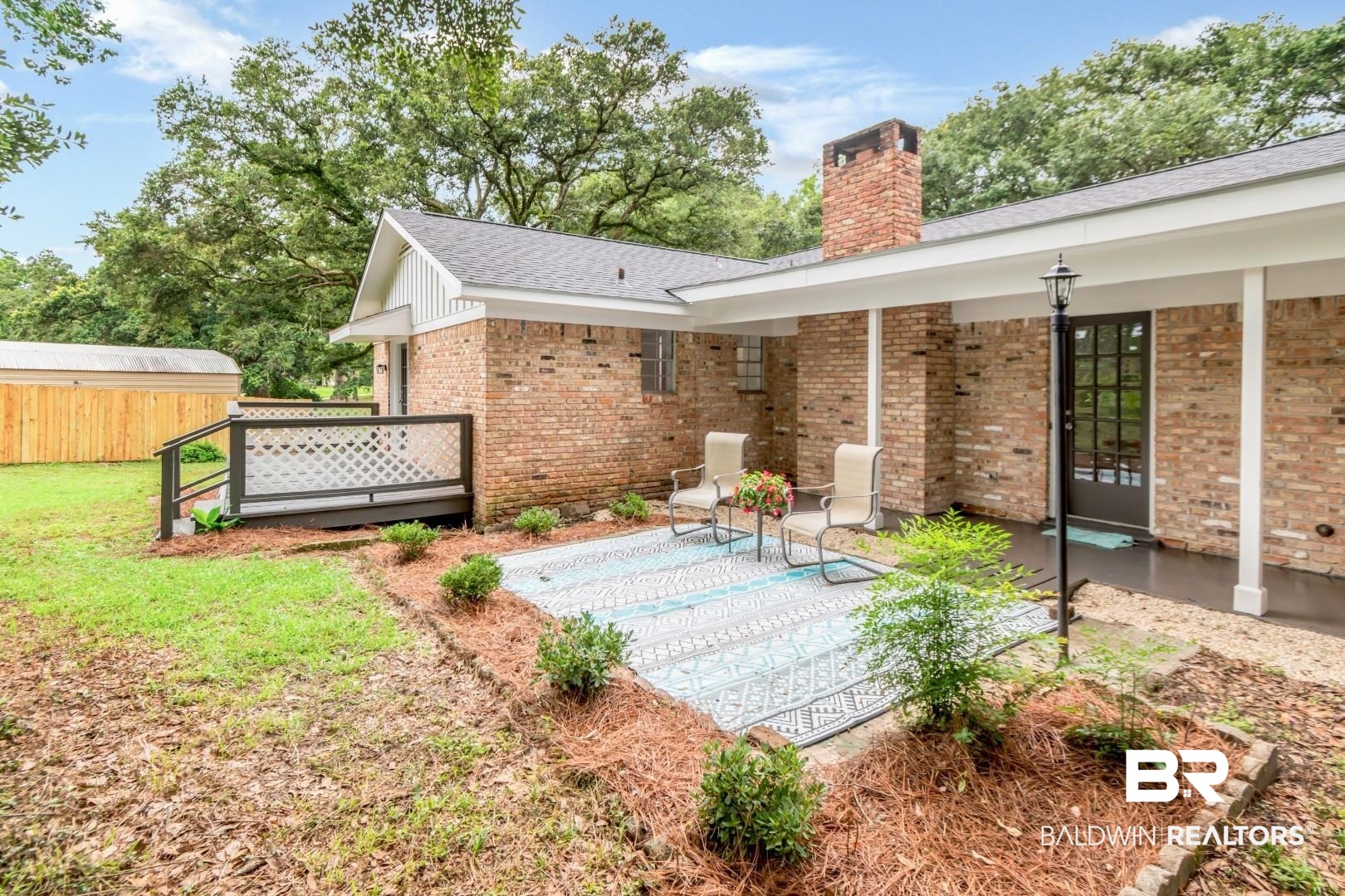 5217 Perin Road Mobile, AL 36693 - Photo 28 of 45 Rear exterior featuring a brick facade, covered patio, outdoor light fixture, and a black paneled door
