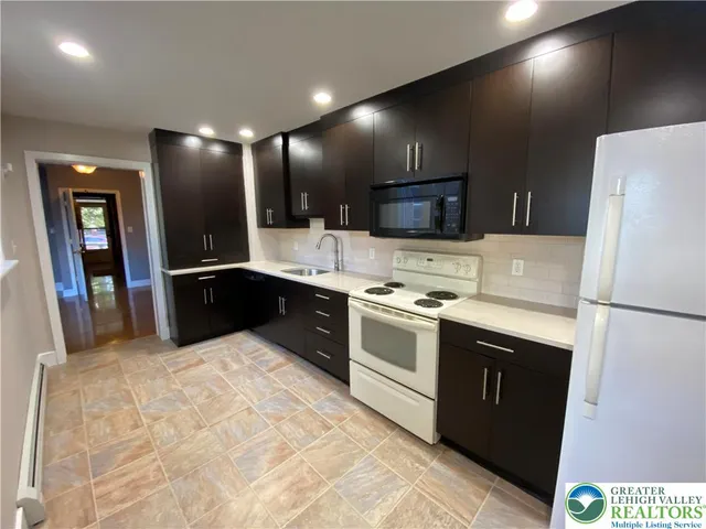 a large kitchen with stainless steel appliances a sink and a refrigerator