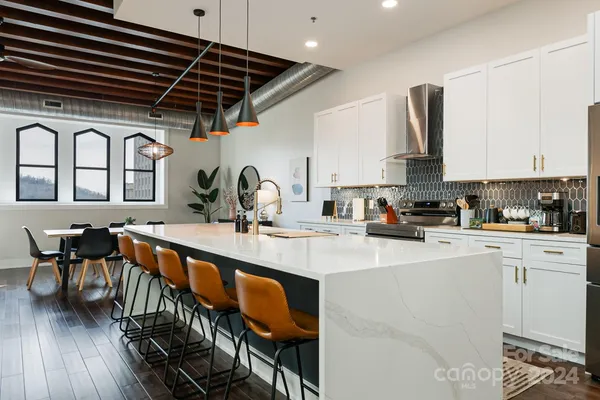a kitchen with stainless steel appliances granite countertop a sink a stove and chairs