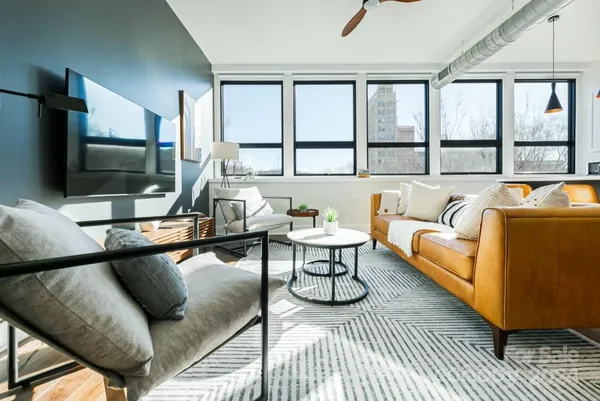 a living room with furniture a flat screen tv and a large window