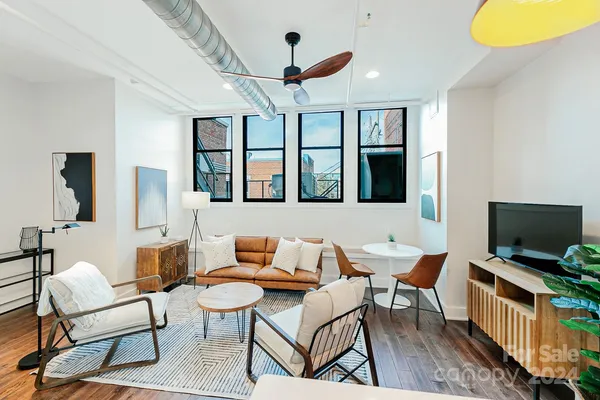 a living room with furniture a flat screen tv and a window