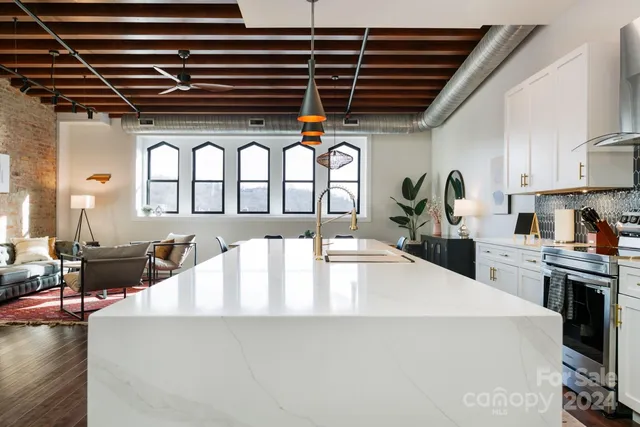 a large kitchen with a large window a counter space a sink and stainless steel appliances