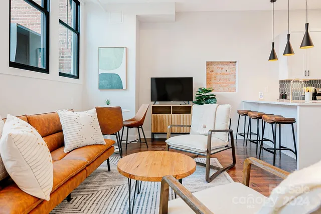 a living room with furniture a flat screen tv and kitchen view