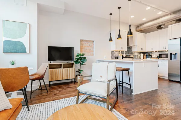a living room with stainless steel appliances kitchen island granite countertop furniture a rug kitchen view and a flat screen tv