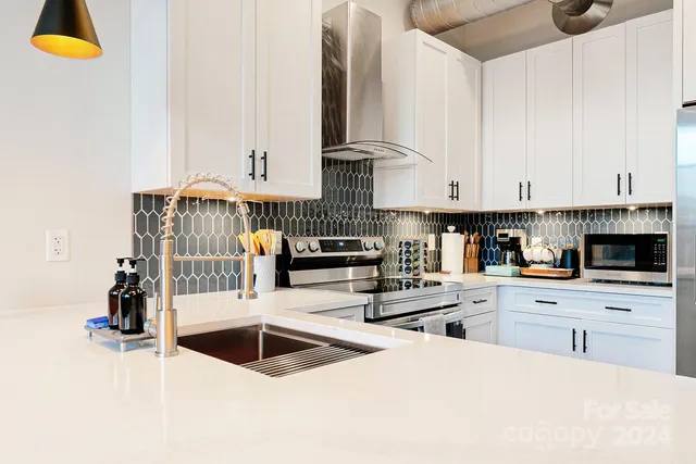a kitchen with stainless steel appliances kitchen island granite countertop a stove and white cabinets