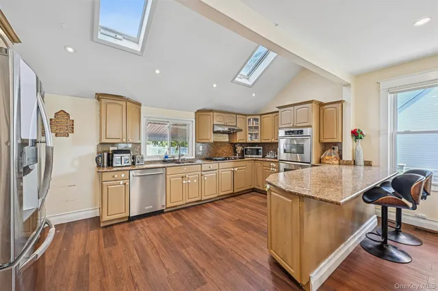 a kitchen with stainless steel appliances granite countertop a refrigerator a sink dishwasher a stove and white countertops with wooden floor