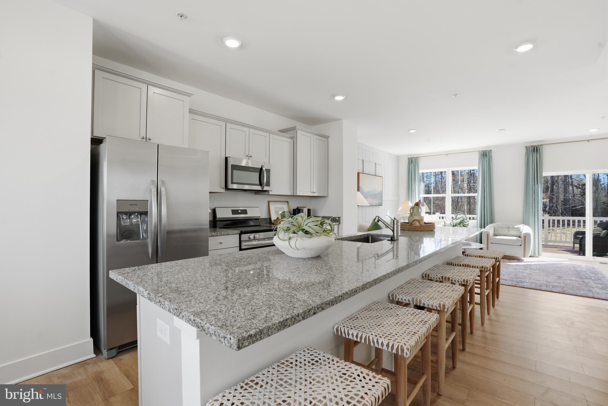 7610 River Reach Road Baltimore, MD 21244 - Photo 2 of 16 a kitchen with stainless steel appliances granite countertop a stove a sink a refrigerator and white cabinets with wooden floor