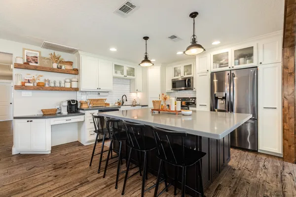 a kitchen with stainless steel appliances a dining table chairs stove and refrigerator