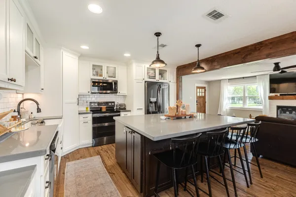 a kitchen with stainless steel appliances granite countertop a kitchen island a stove a table and chairs