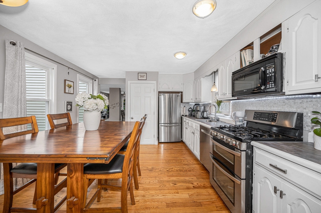 44 Mill Street Revere, MA 02151 - Photo 13 of 36 a kitchen with stainless steel appliances granite countertop a stove top oven a sink dishwasher a dining table and chairs with wooden floor