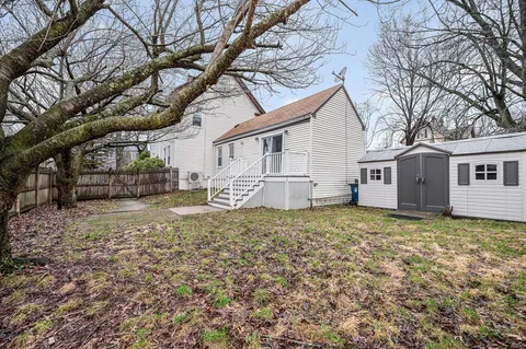 a backyard of a house with large trees and barbeque oven
