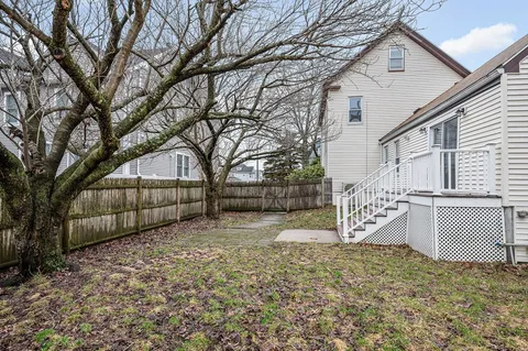 a view of backyard with a large tree and wooden fence