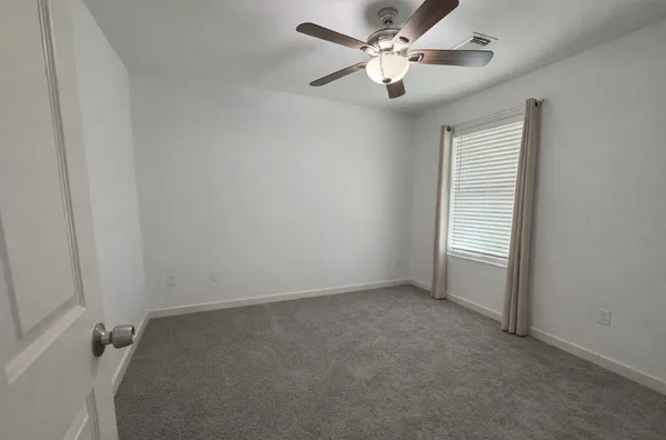 an empty room with a ceiling fan and a window