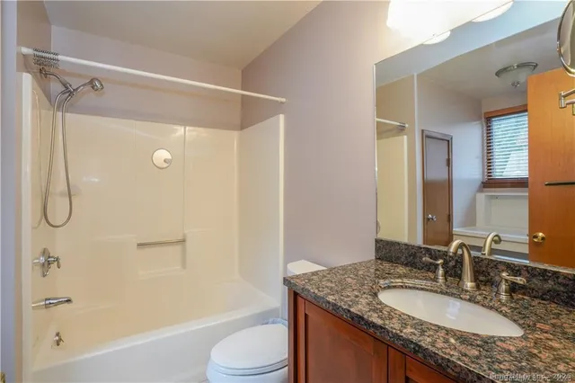 a bathroom with a granite countertop sink toilet mirror and shower