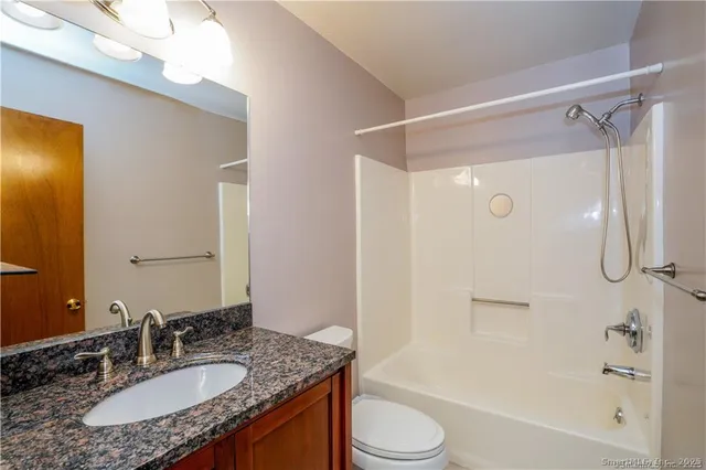 a bathroom with a granite countertop sink toilet and shower